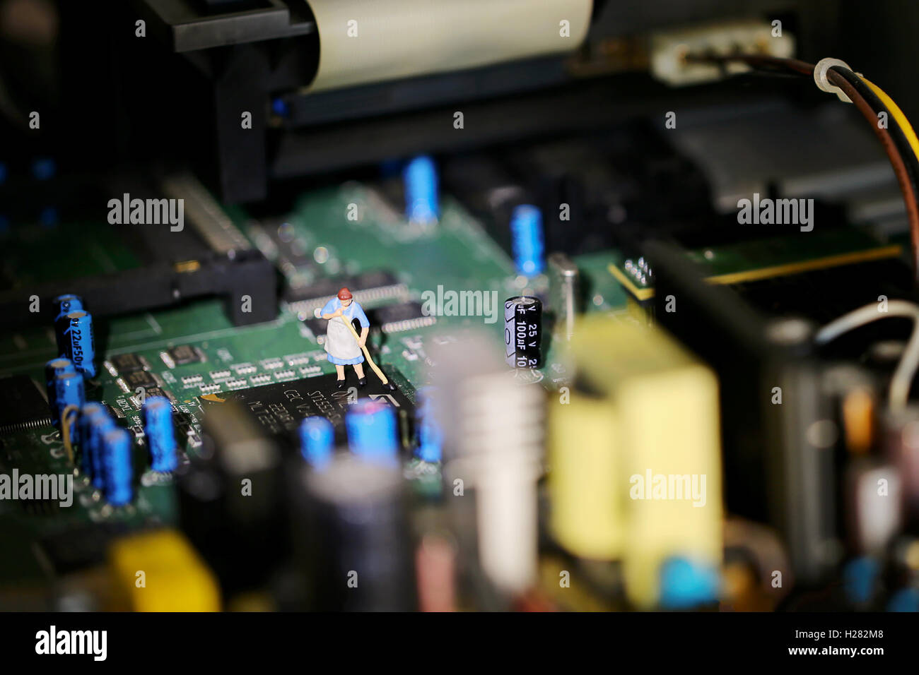 A small oo model scale figure of a cleaner sweeping a dirty electronic circuit board inside a computer Stock Photo