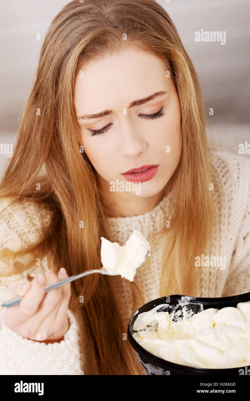 Young depressed woman is eating big bowl of ice creams to comfor Stock