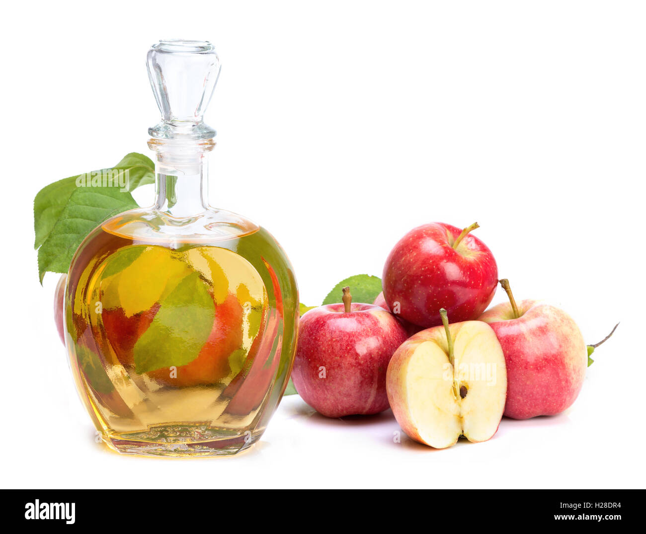 apple cider vinegar in a glass vessel and red apples isolated on white ...
