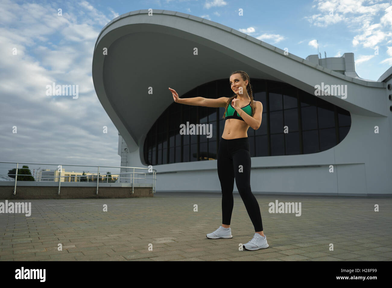 Concept: healthy lifestyle, sport. Attractive happy girl fitness trainer do outdoor workout at modern downtown urban area during Stock Photo