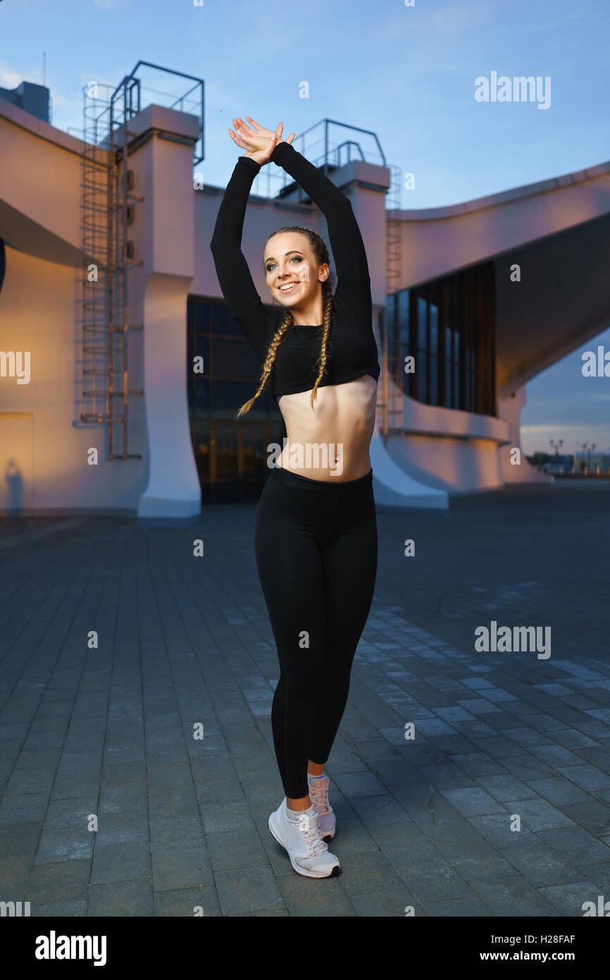 Concept: healthy lifestyle, sport. Attractive happy girl fitness trainer do outdoor workout at modern downtown urban area during Stock Photo