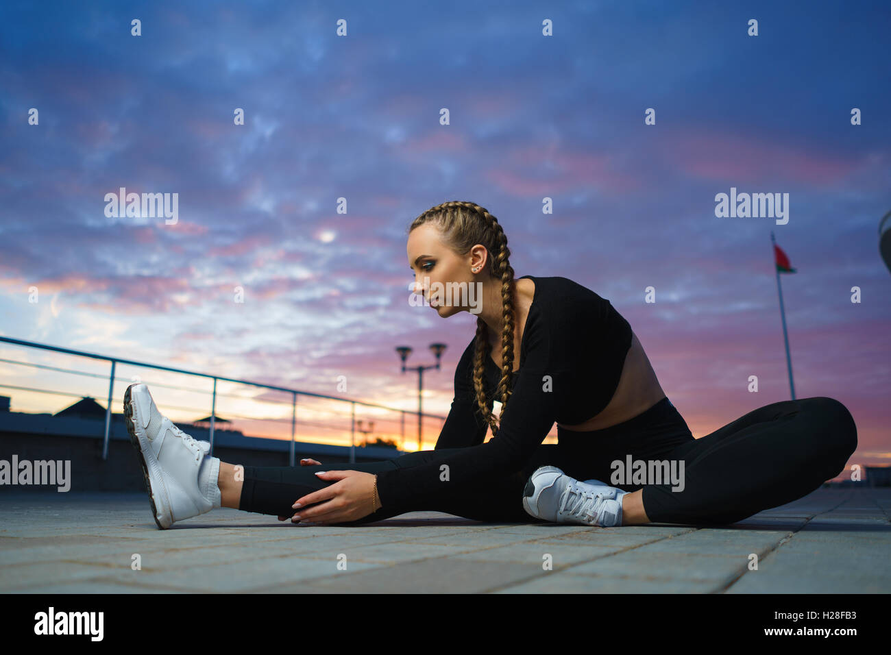 Concept: healthy lifestyle, sport. Attractive happy girl fitness trainer stretch outdoor workout at modern downtown urban area d Stock Photo