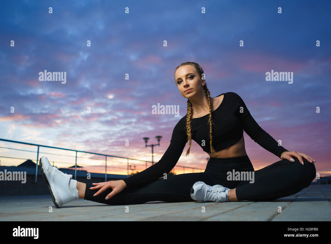 Concept: healthy lifestyle, sport. Attractive happy girl fitness trainer stretch outdoor workout at modern downtown urban area d Stock Photo