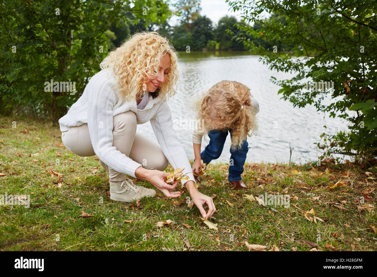 Woman and child collecting leaves in autumn at park Stock Photo