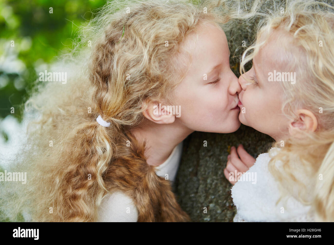 Two little sister girls kissing with sibling love and affection Stock Photo