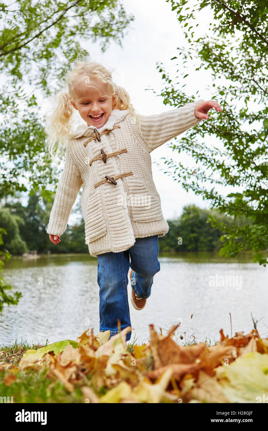 Smiley little blond girl with autumn leaves at the park Stock Photo - Alamy