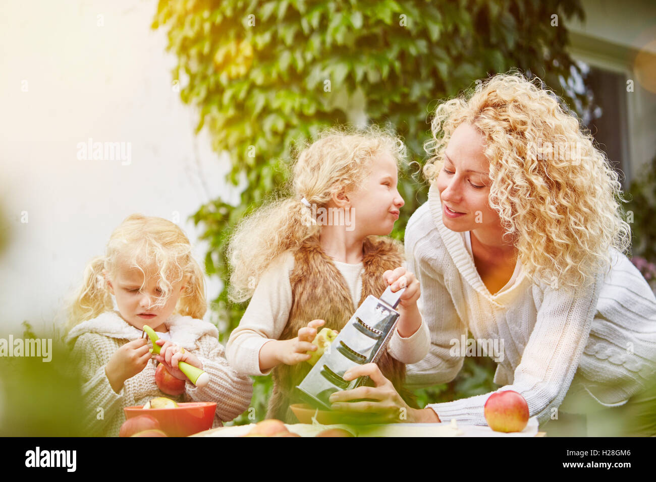 Mother and children rubbing apples for baking Stock Photo
