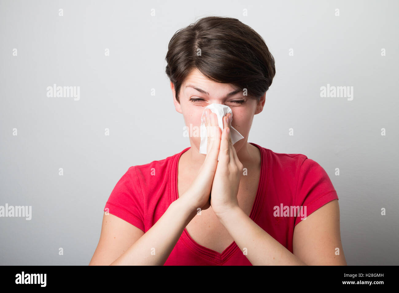 Young woman blowing her nose too hard Stock Photo