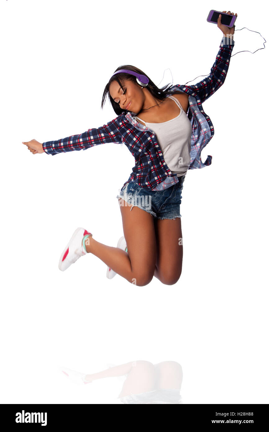 Beautiful happy teenager jumping dancing jamming listening to music, on white. Stock Photo