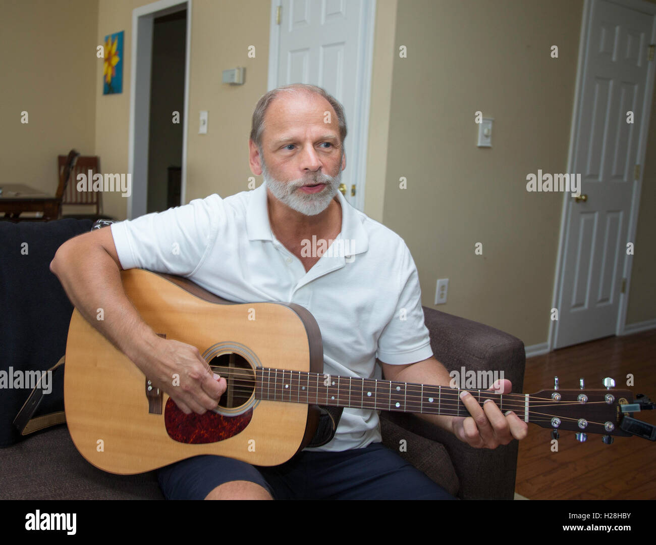 Man playing guitar in his apartment Stock Photo