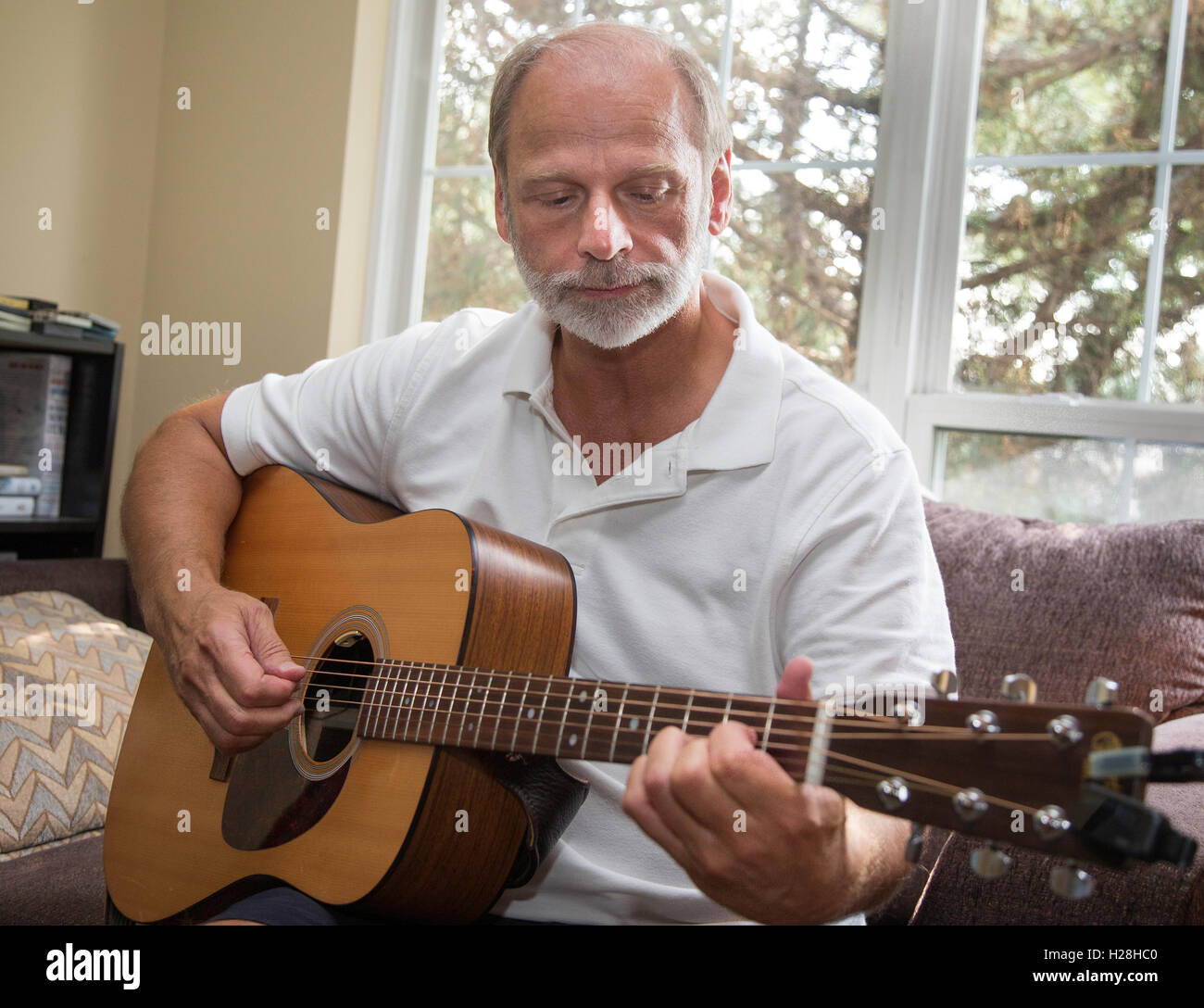 Man playing guitar in his apartment Stock Photo