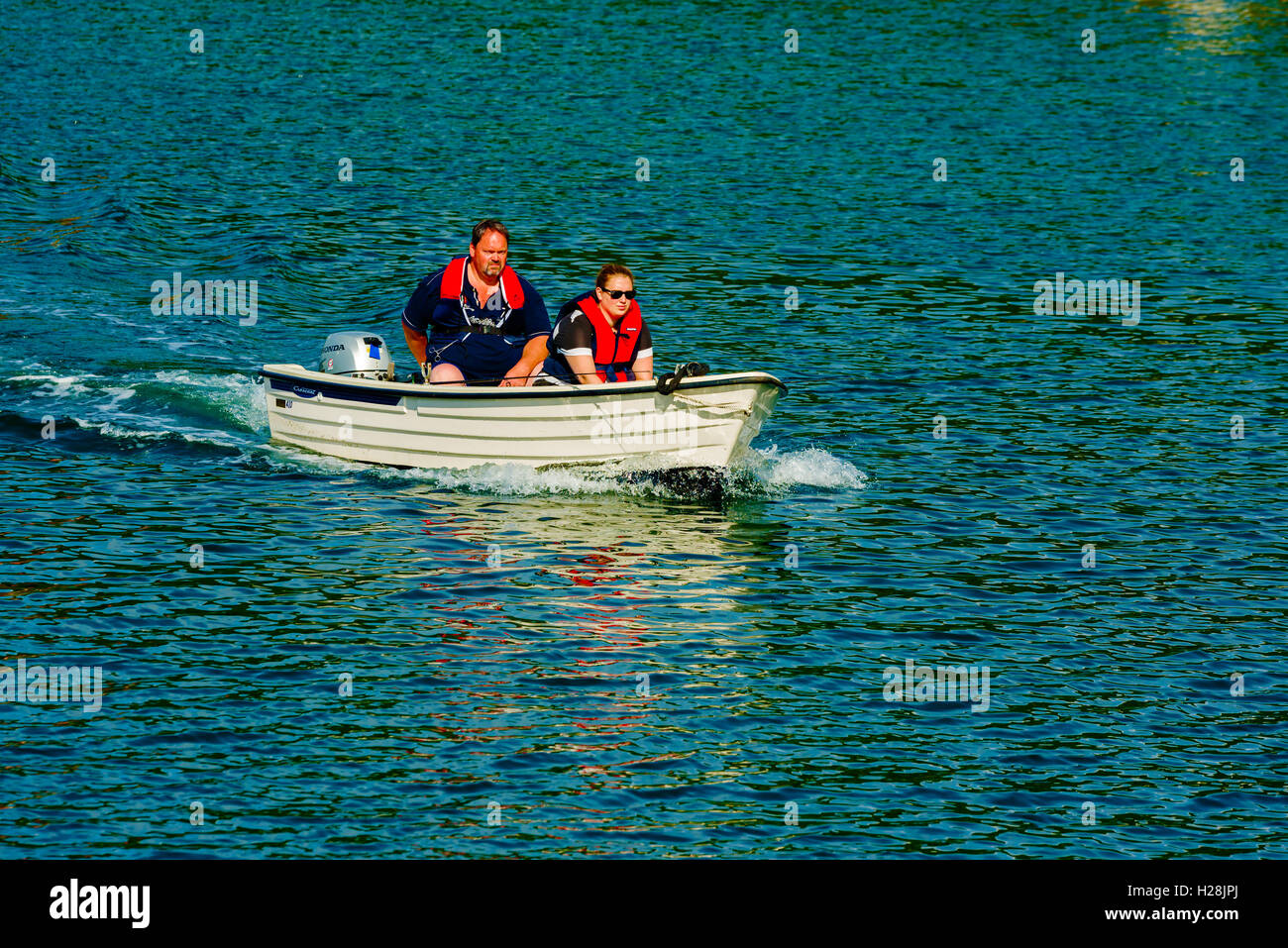 Askeron, Sweden - September 9, 2016: Environmental documentary of adult couple traveling in small open motorboat. Stock Photo