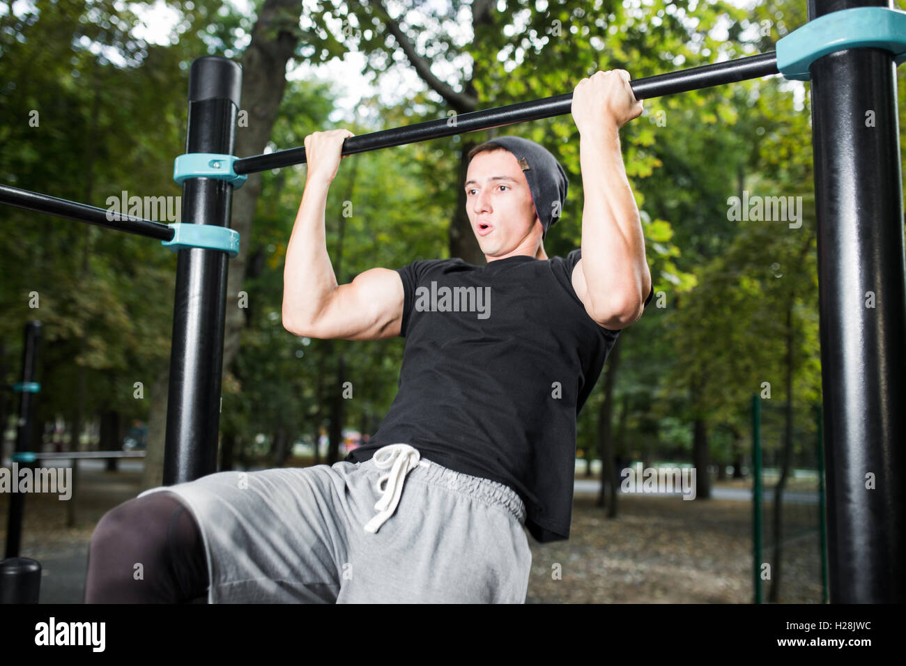Young man doing pull ups on horizontal bar outdoors, workout, sp Stock ...