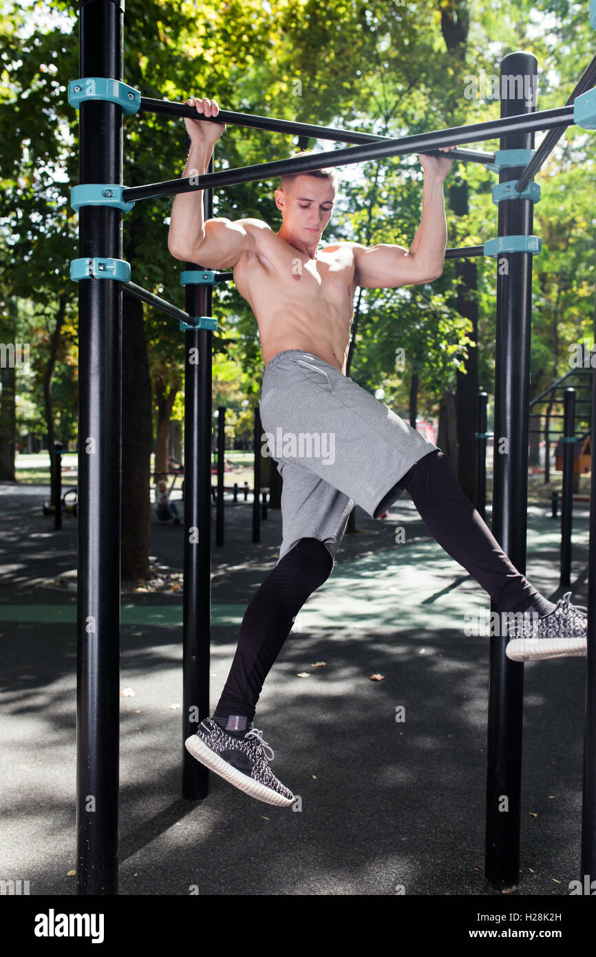 Young man doing pull ups on horizontal bar outdoors, workout, sp Stock ...