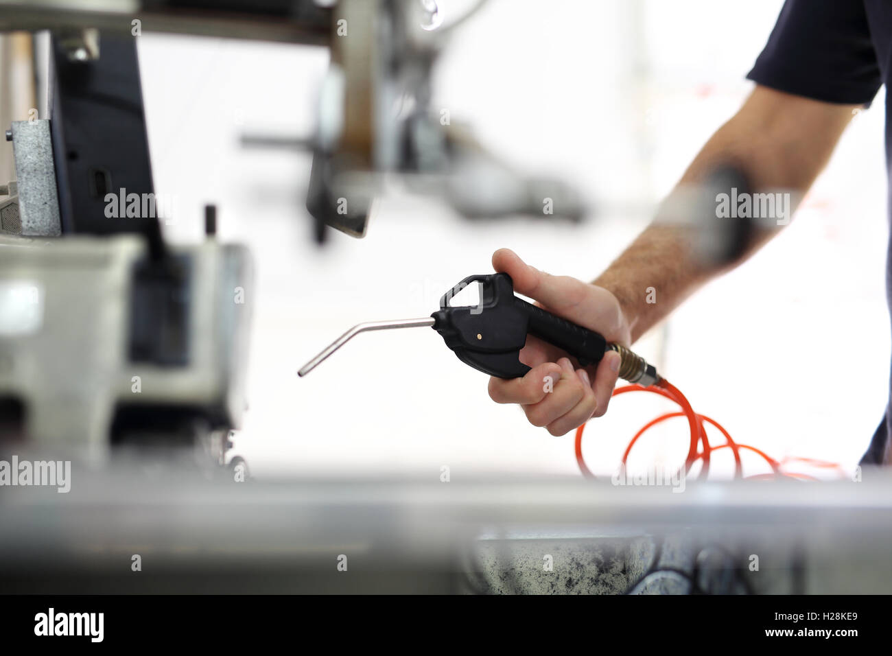 worker cleans the sewing machine with compressed air Stock Photo