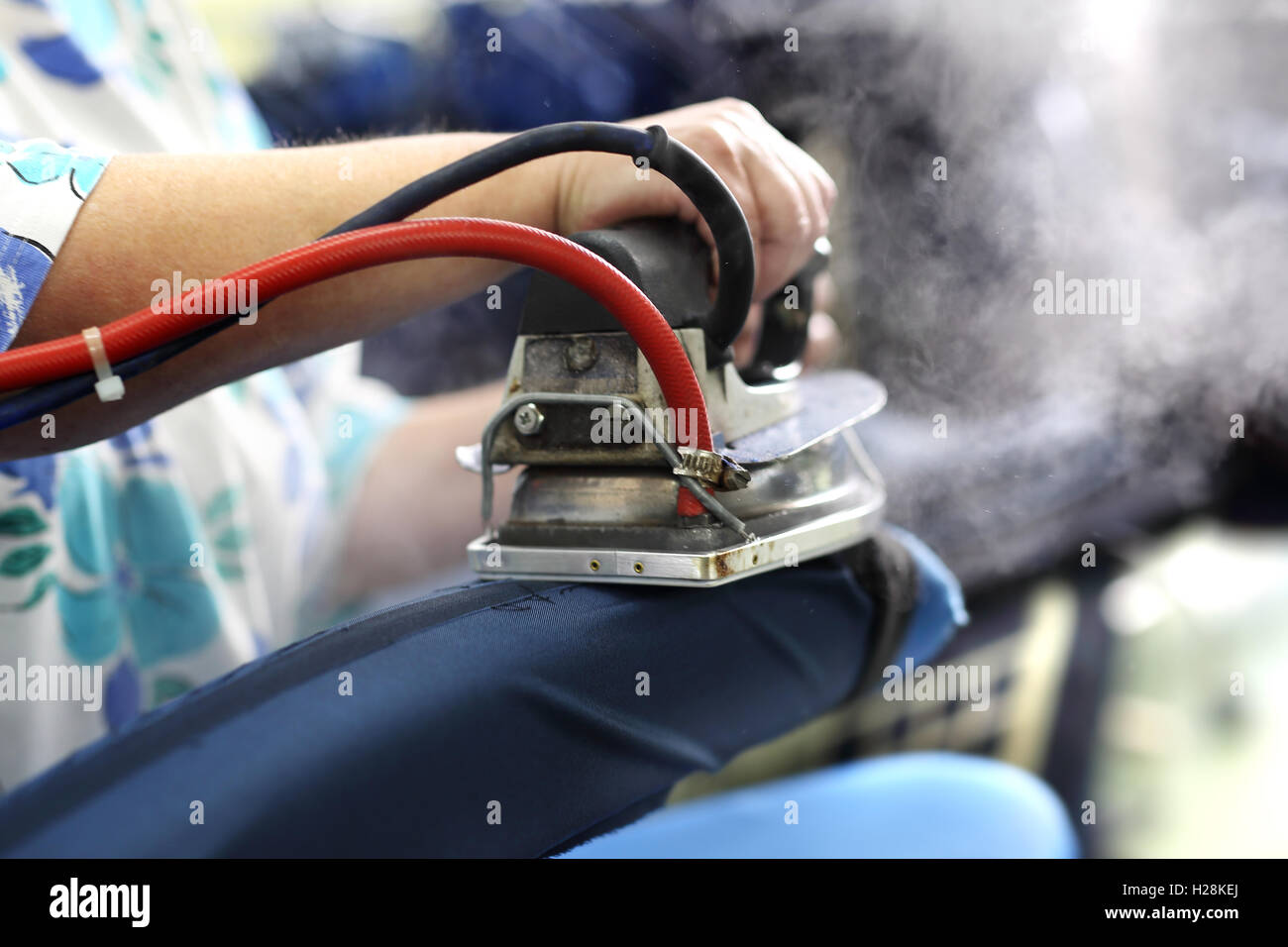 Clothing industry. Ironing steam. Presser in sewing clothes pressed. Stock Photo