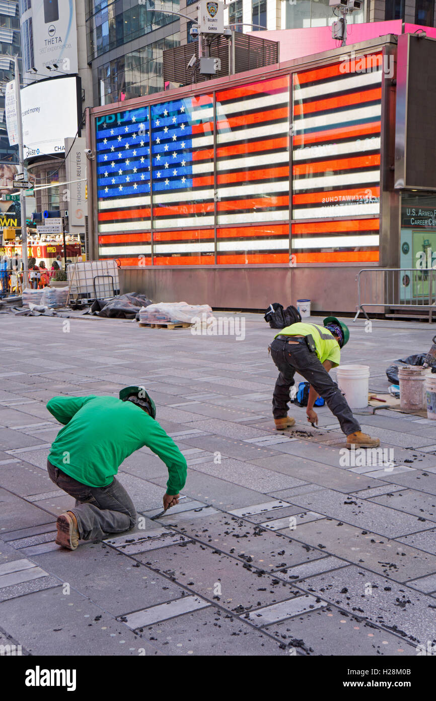 Two construction workers working on paving a pedestrian area in the Times Square section of Midtown Manhattan, New York City. Stock Photo