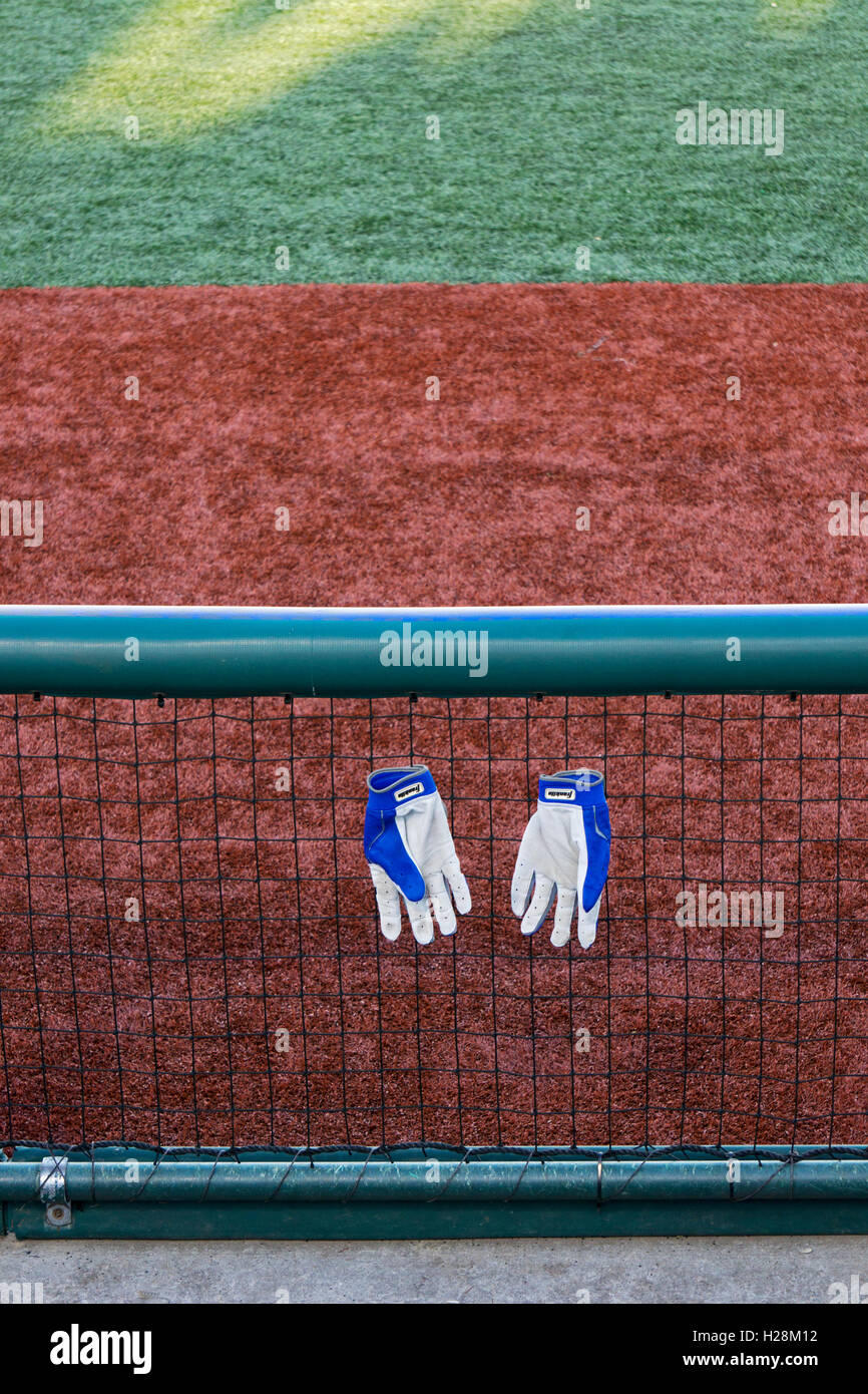Baseball hitting gloves hanging on a fence near a dugout at MCU Park in Coney Island Brooklyn, NY at the World Baseball Classic Stock Photo