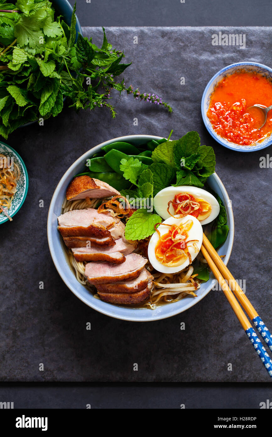 Vietnamese pho with duck with crispy skin, bean sprouts and egg, chili
