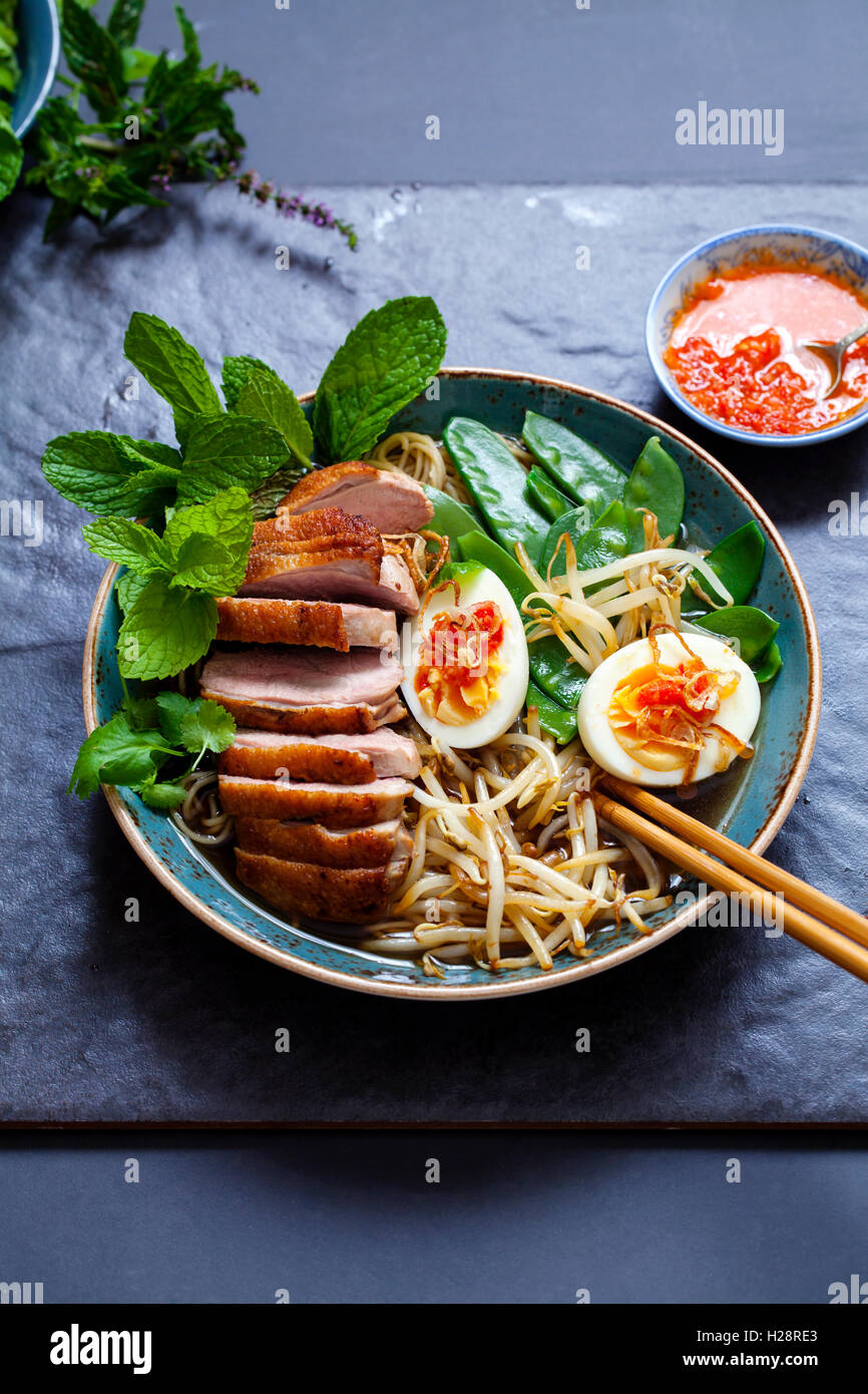 Vietnamese pho with duck with crispy skin, bean sprouts and egg, chili