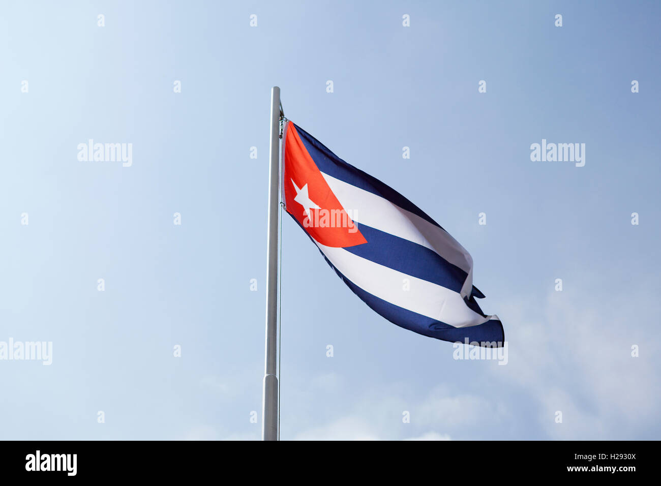 National flag of Cuba on a flagpole in front of blue sky Stock Photo
