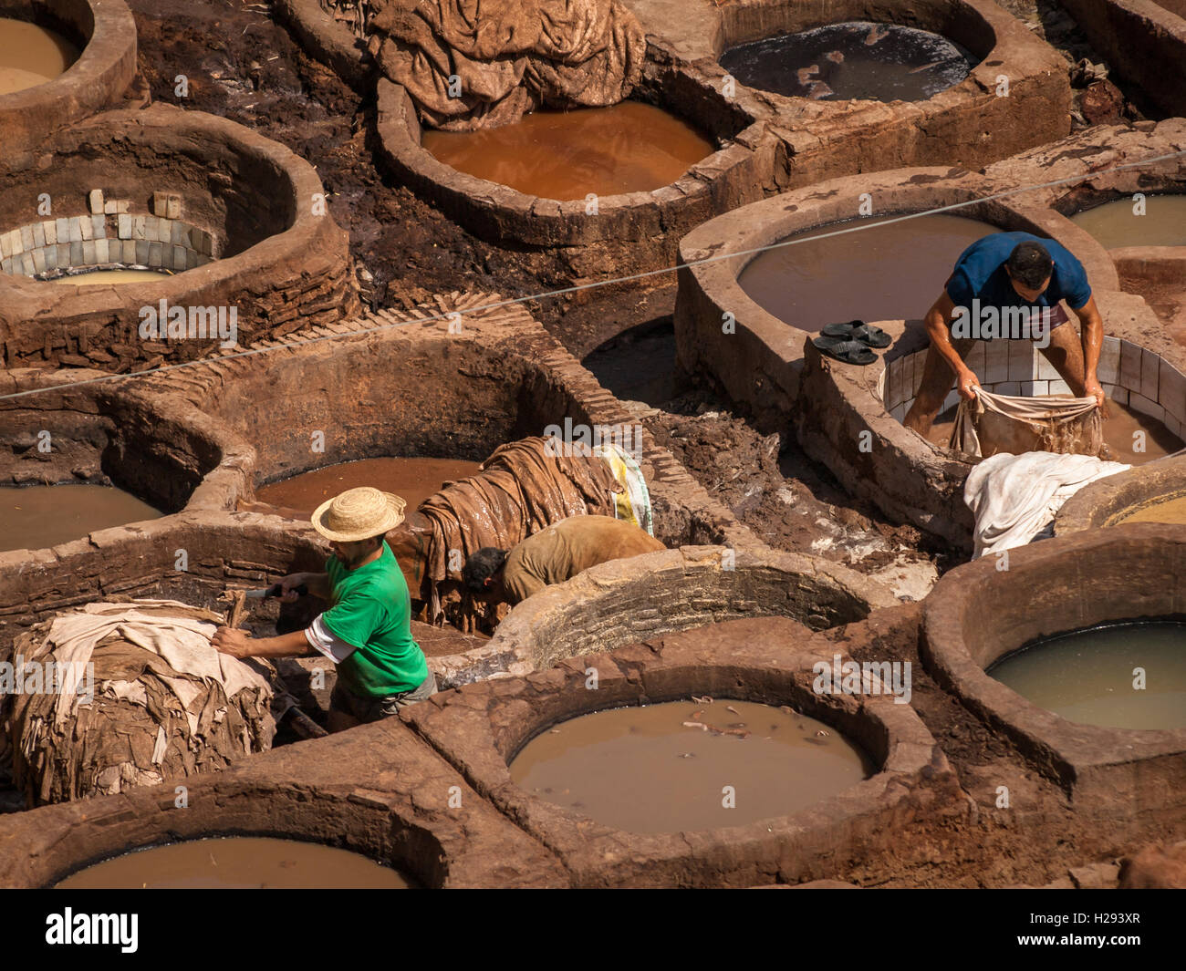 Men dipping leather into tanning vats in Chouwara tannery in Fez (Morocco) Stock Photo