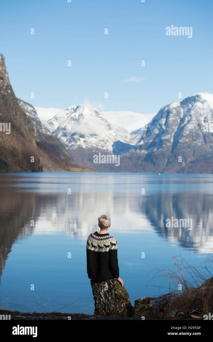 A woman looks out onto a Norwegian fjord lake in Flam, Norway. Stock Photo