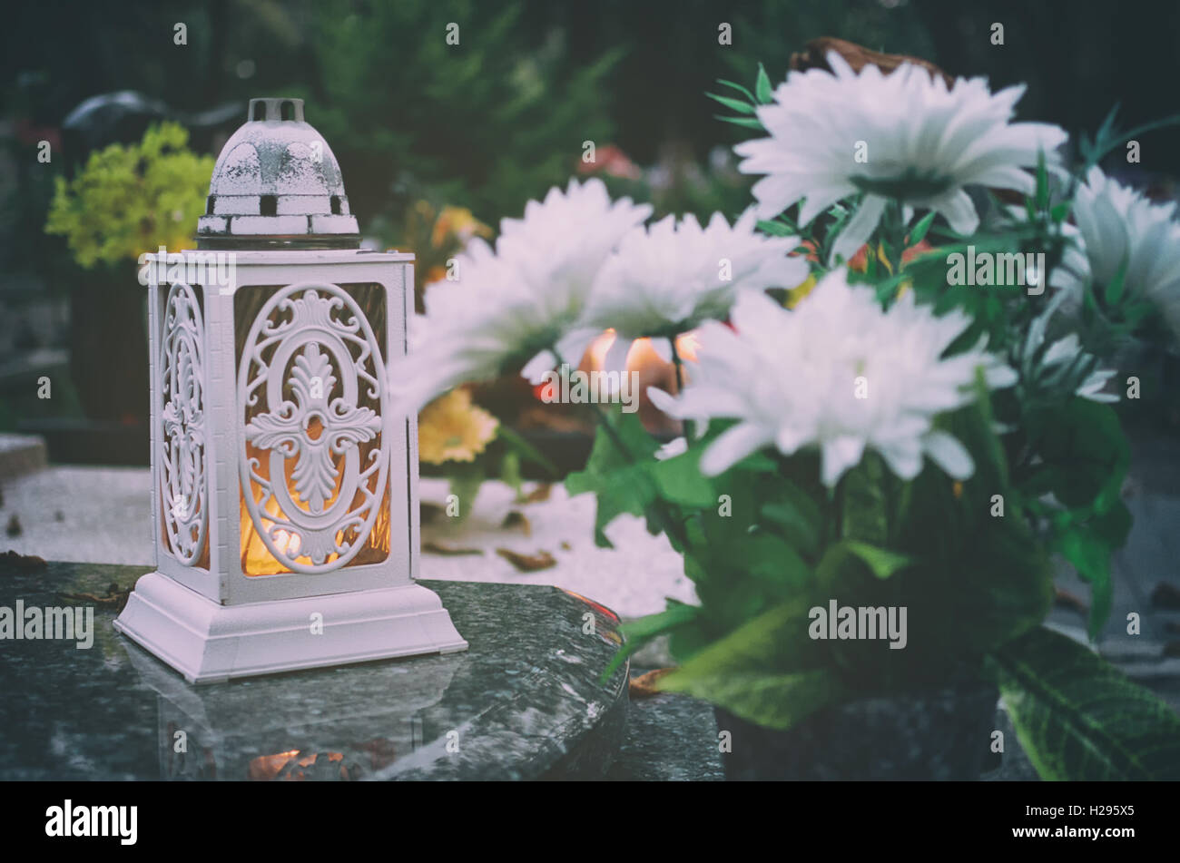 Lantern with a candle and flowers on the grave. Stock Photo