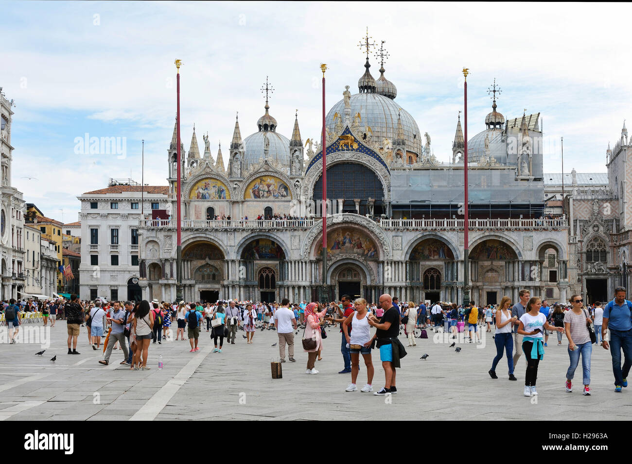 Tourists on the San Marco square in front of the St. Mark's Basilica of Venice in Italy. Stock Photo