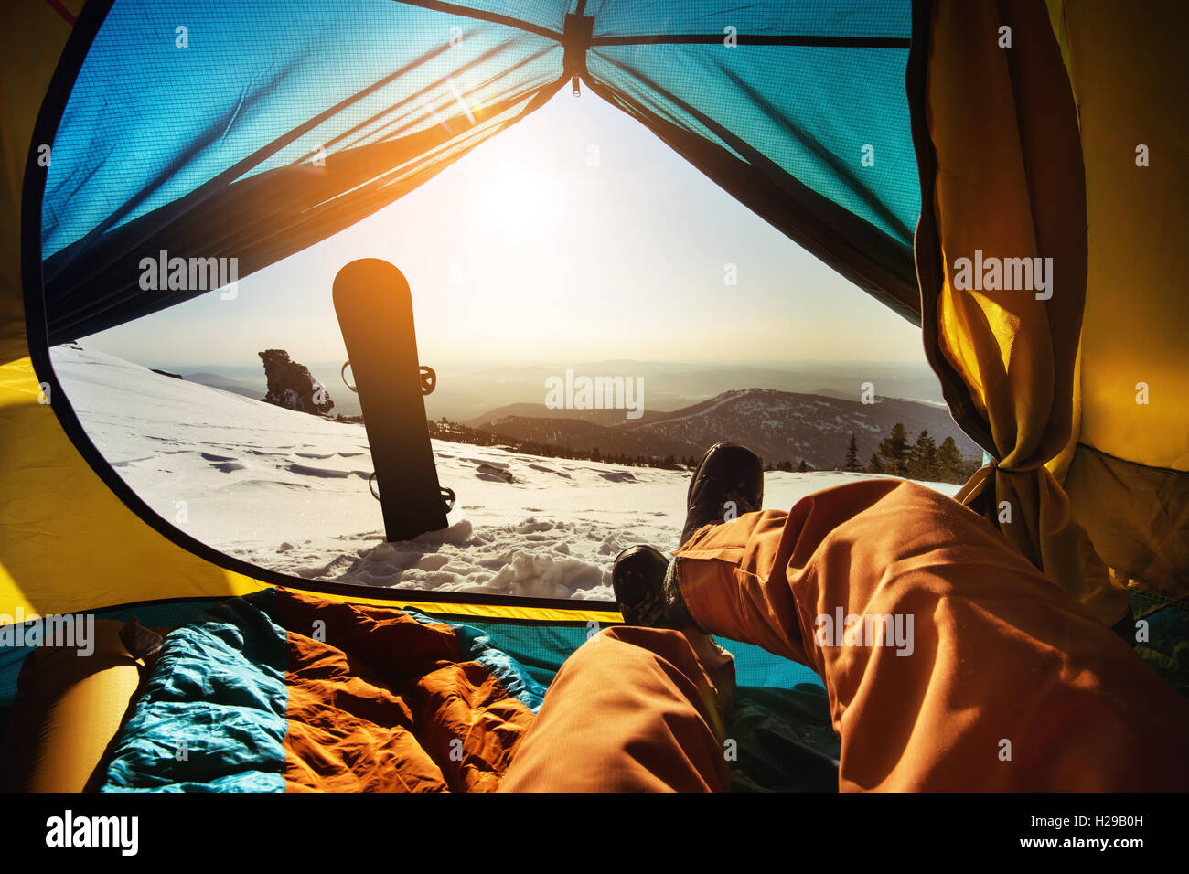 Snowboarder relaxing in tent on background of sunset Stock Photo