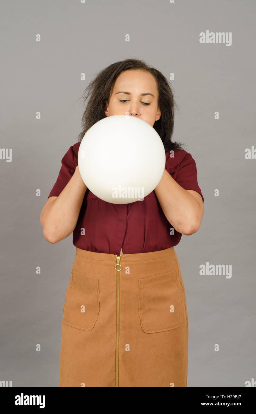 Adult woman blowing up a huge white balloon Stock Photo