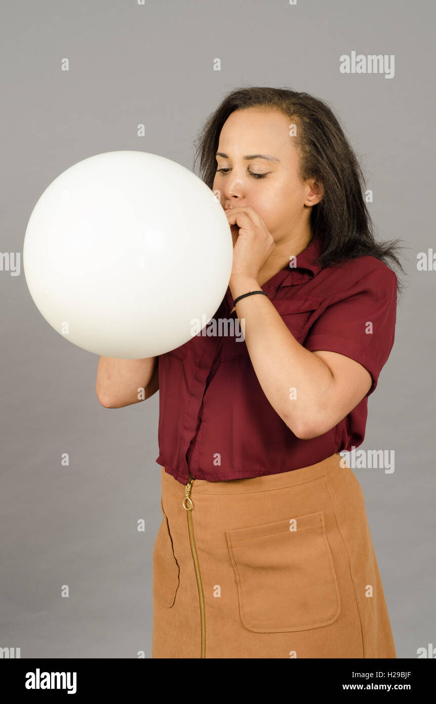 Adult woman blowing up a huge white balloon Stock Photo
