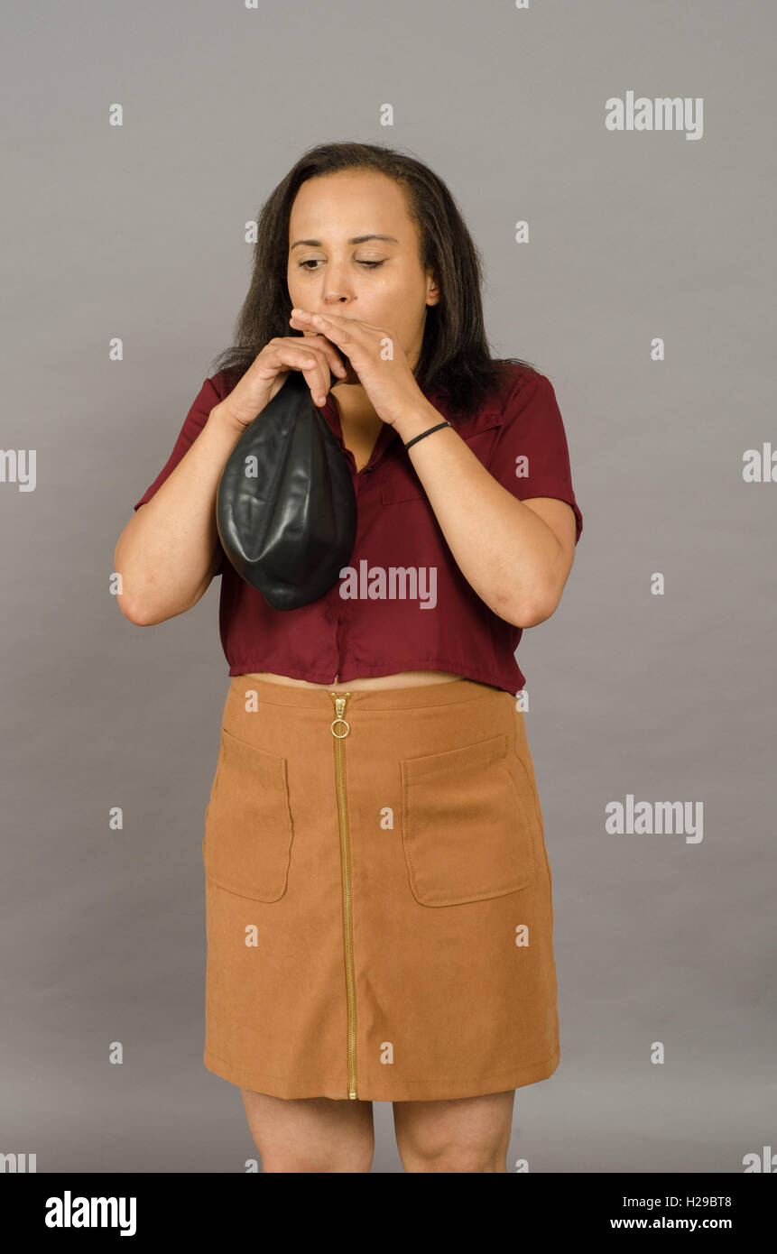 Adult woman blowing up a huge black balloon Stock Photo