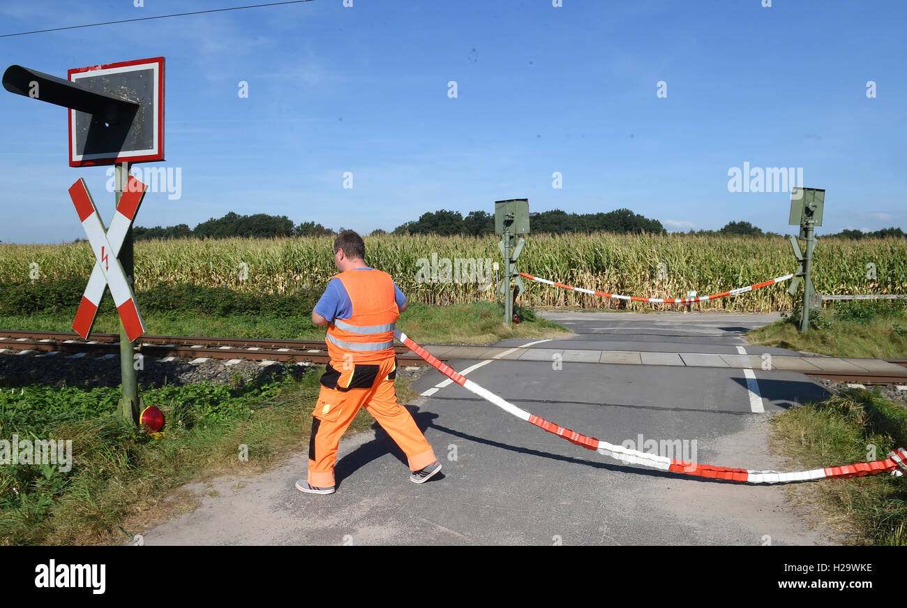 Holtgast, Germany. 21st Sep, 2016. An employee of a saecurity firm hangs barrier tape in front of a railway vcrossing in Holtgast, Germany, 21 September 2016. Security people have been guarding this railway crossing for months because the light of the signalling installation is faulty. PHOTO: CARMEN JASPERSEN/dpa/Alamy Live News Stock Photo