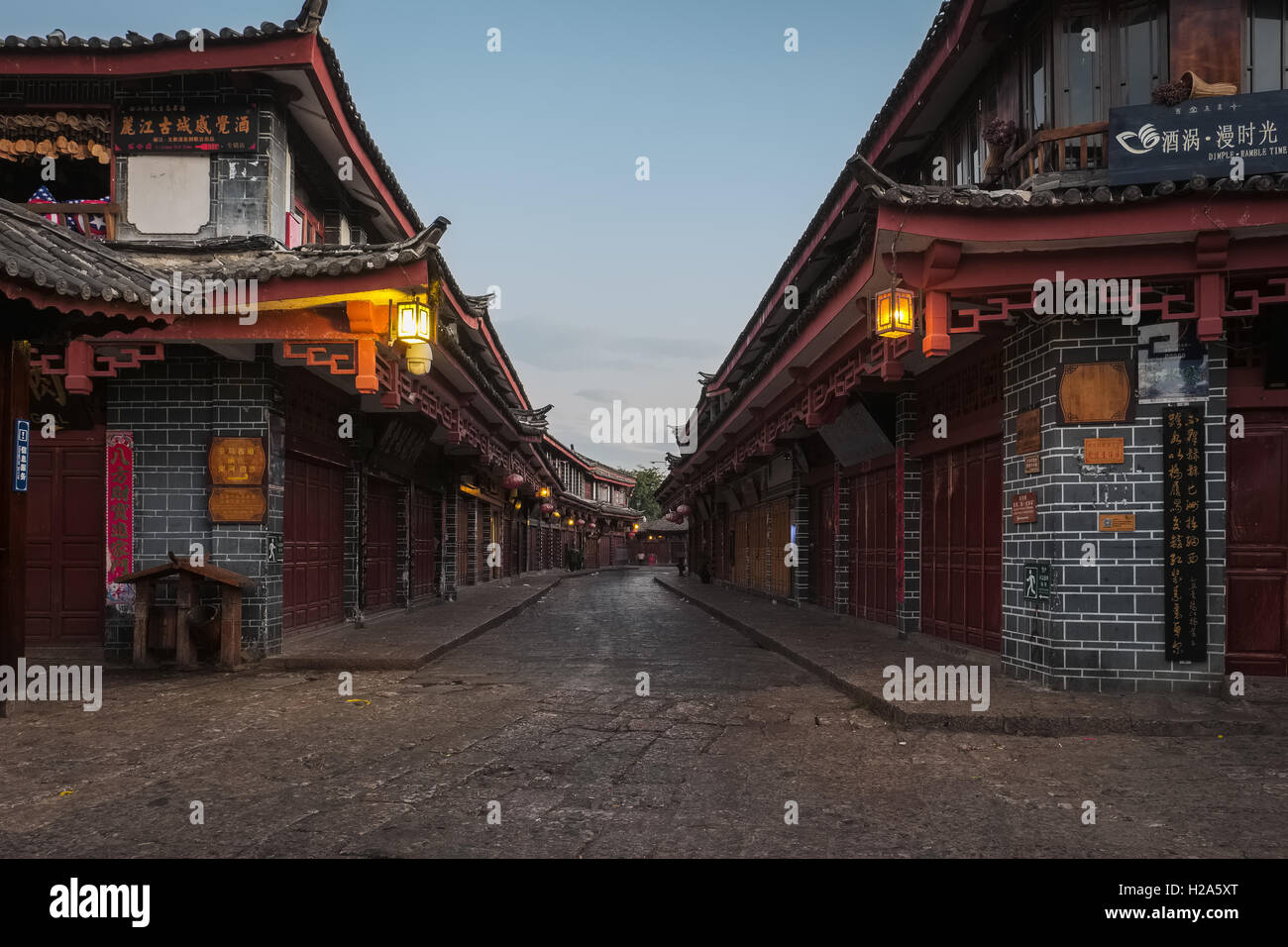 Quiet street with traditional Chinese shops and restaurant and hanging lanterns at dawn in Lijiang, China Stock Photo