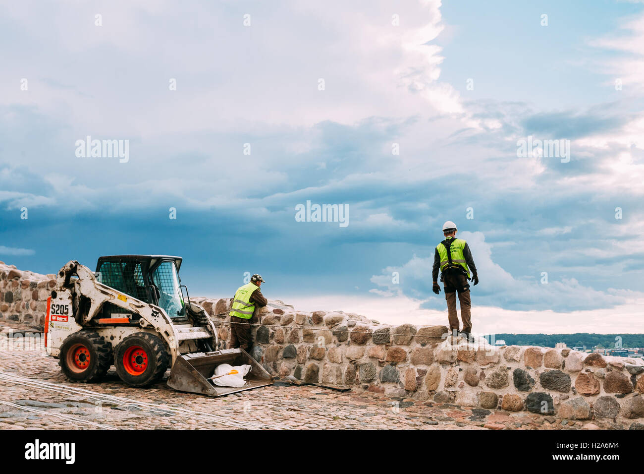 Vilnius, Lithuania - July 04, 2016:  Two Workers Men With Mini Dozer At The Service Maintenance Of Ancient Stone Wall Near The G Stock Photo