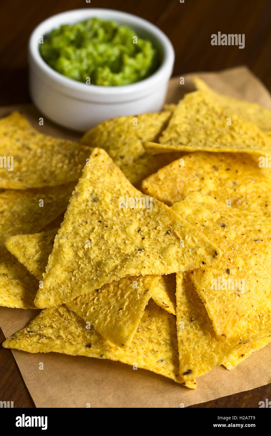 Corn tortilla chips with avocado dip in the back, photographed with