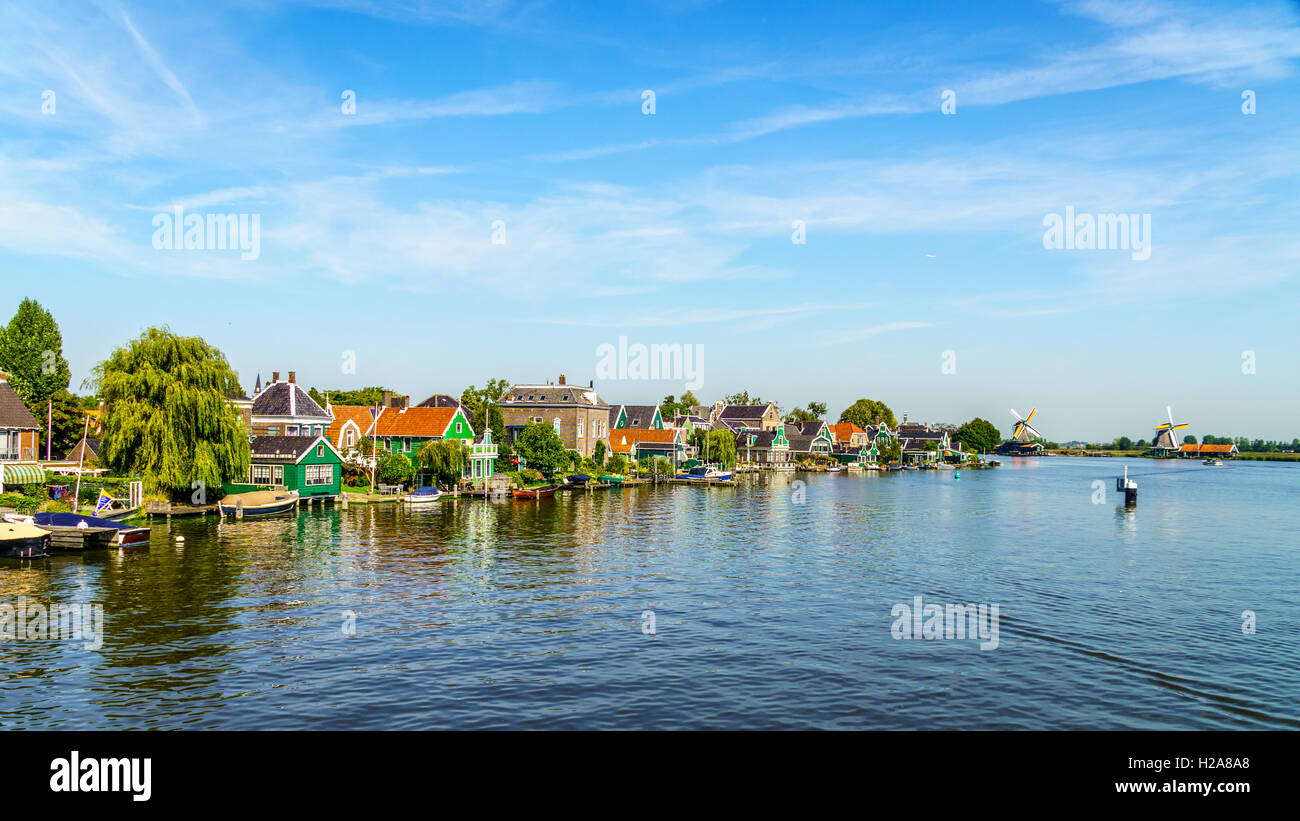View from the Zaan River of old Dutch Windmills and historic houses along the river at the historic village of Zaanse Schans in the Netherlands Stock Photo