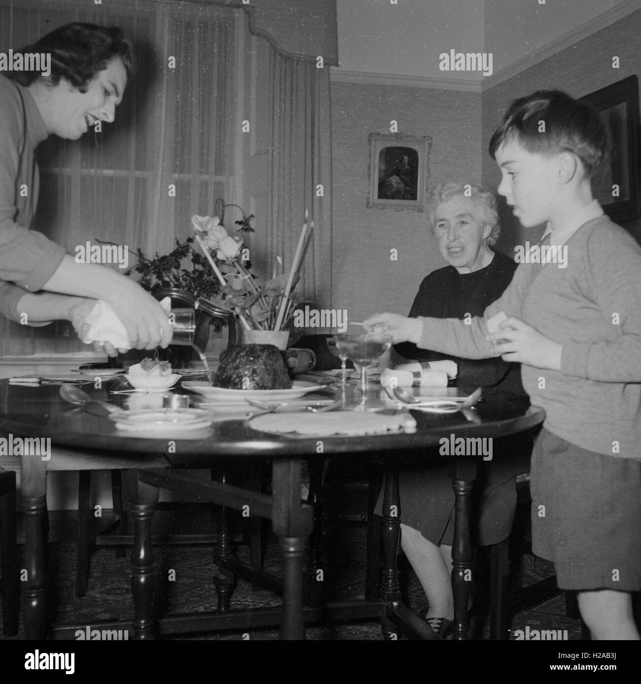 A mum lets her son set light to some brandy on the Christmas pudding social history, England c1960. Photo by Tony Henshaw Stock Photo