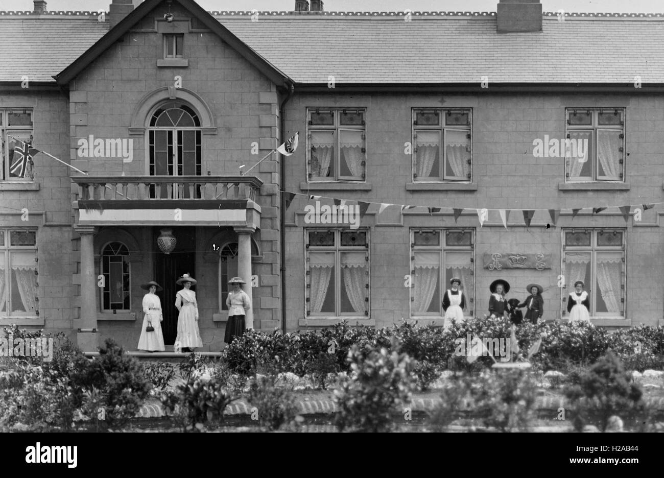 Country house with bunting and flags with possible family and household staff and Newark Area c1910 (cropped version).  Further details for entire collection in the box of 50 slides -  as written in glass slide box 'Ann Swain 1910, Annie & Georgie Betts 1910, Mr Starbuck, Lily & Ethel 1909, Kate & Family, Georgie & Tommy Holgate, Group at Newark 1909, Belvoir Castle, Mrs Limb 1910.'  Photo by Tony Henshaw Stock Photo