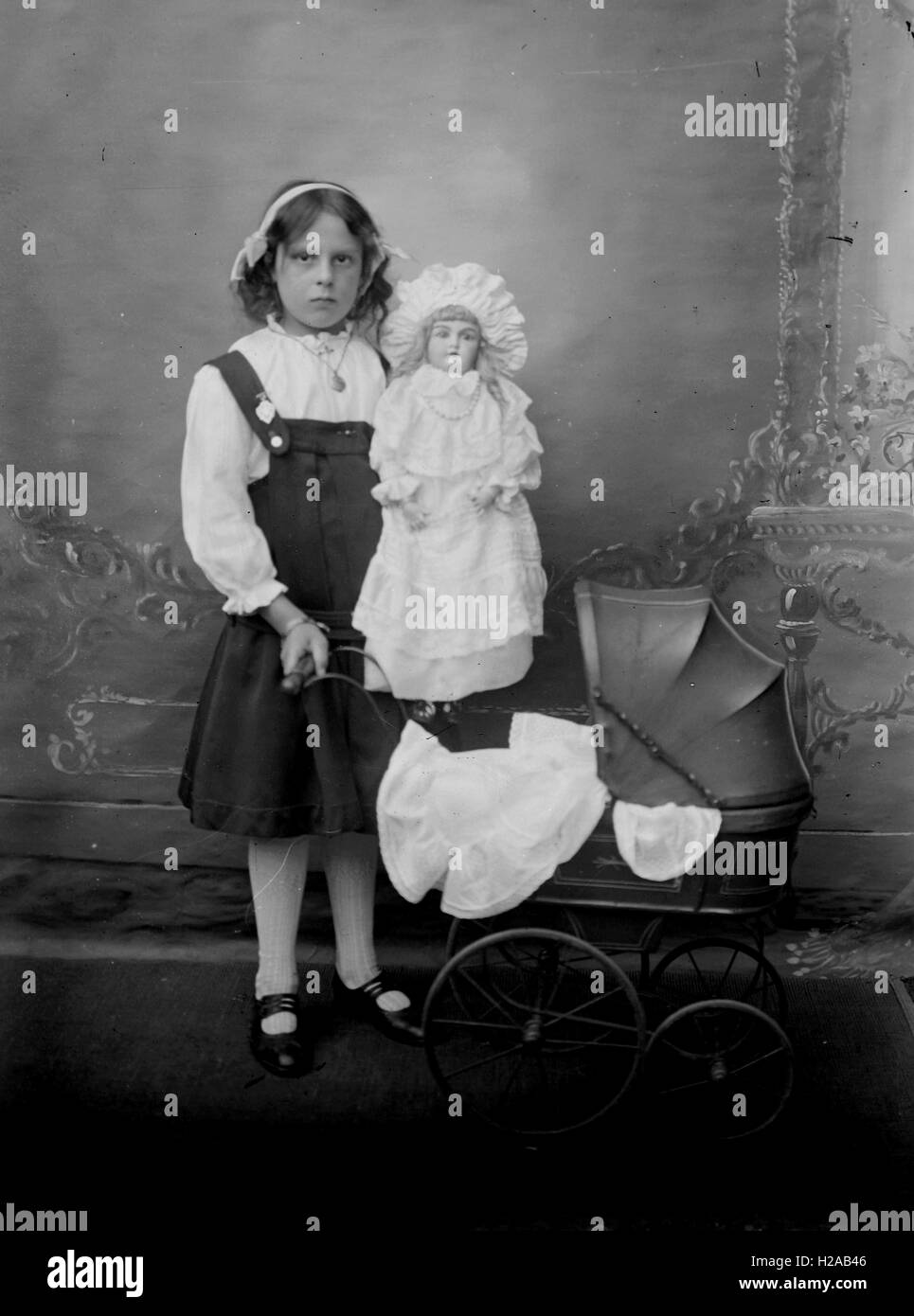 Girl poses with her toy doll and pram, Newark Area c1910.  Further details for entire collection in the box of 50 slides -  as written in glass slide box 'Ann Swain 1910, Annie & Georgie Betts 1910, Mr Starbuck, Lily & Ethel 1909, Kate & Family, Georgie & Tommy Holgate, Group at Newark 1909, Belvoir Castle, Mrs Limb 1910.'  Photo by Tony Henshaw Stock Photo
