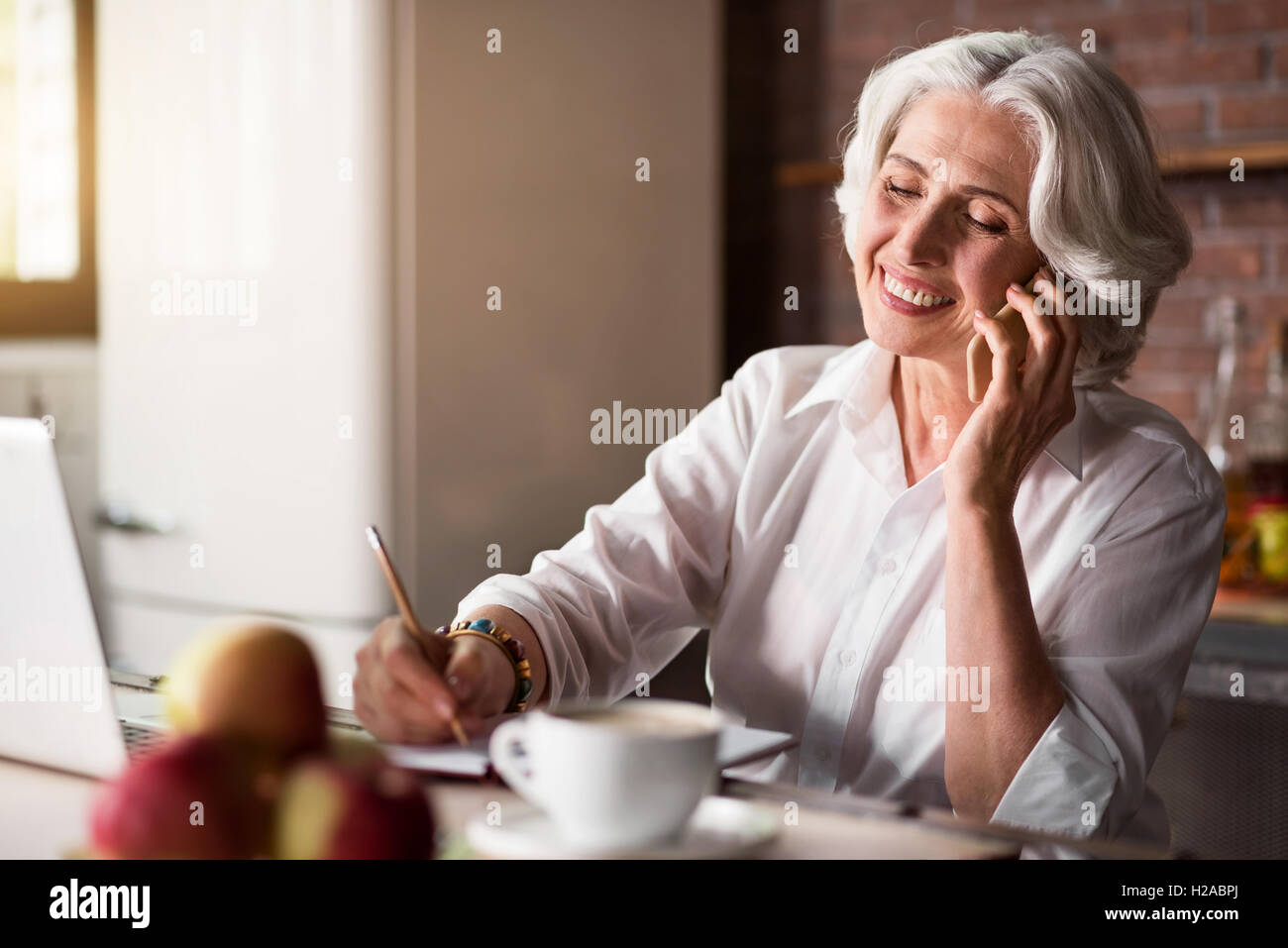 Old woman talking on the phone while taking notes Stock Photo - Alamy