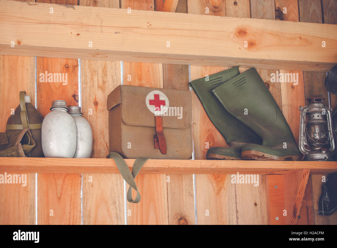 Wooden shelfe with retro surival kit and green boots Stock Photo