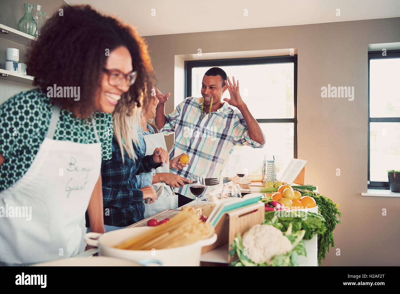 Group of young adults goofing off at table covered with pasta and vegetables for cooking class Stock Photo