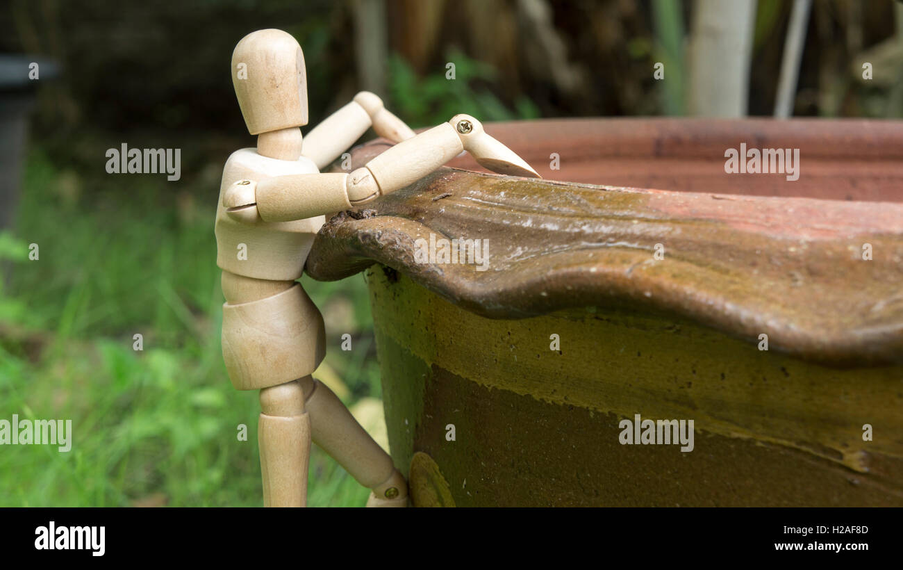wooden human figure climb tree pot garden Stock Photo