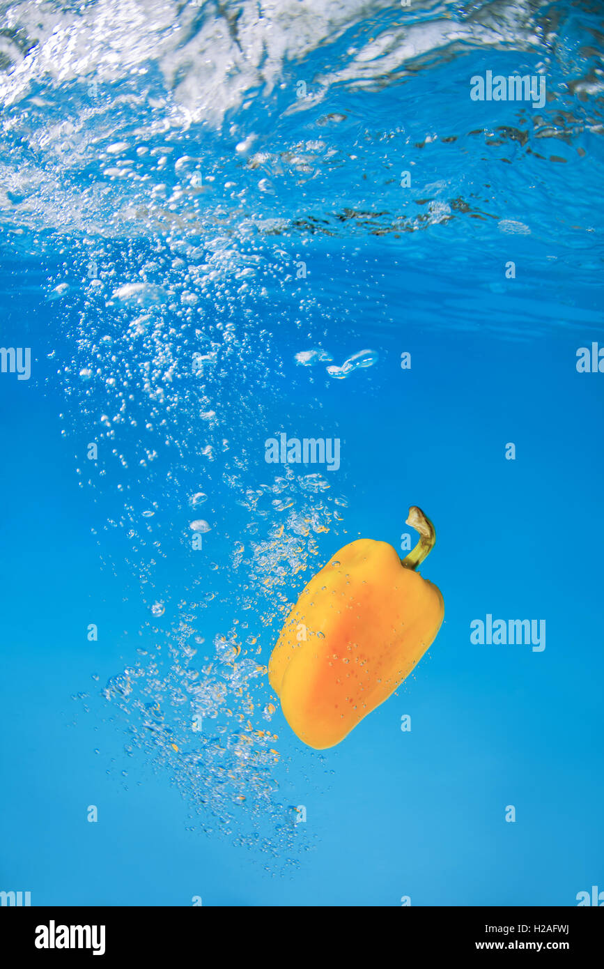 Bell pepper splashing in blue water Stock Photo