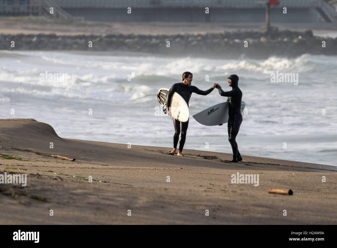 Two surfers congratulate each other after their successful rides in the Pacific Ocean of northern California near Moss Landing. Stock Photo