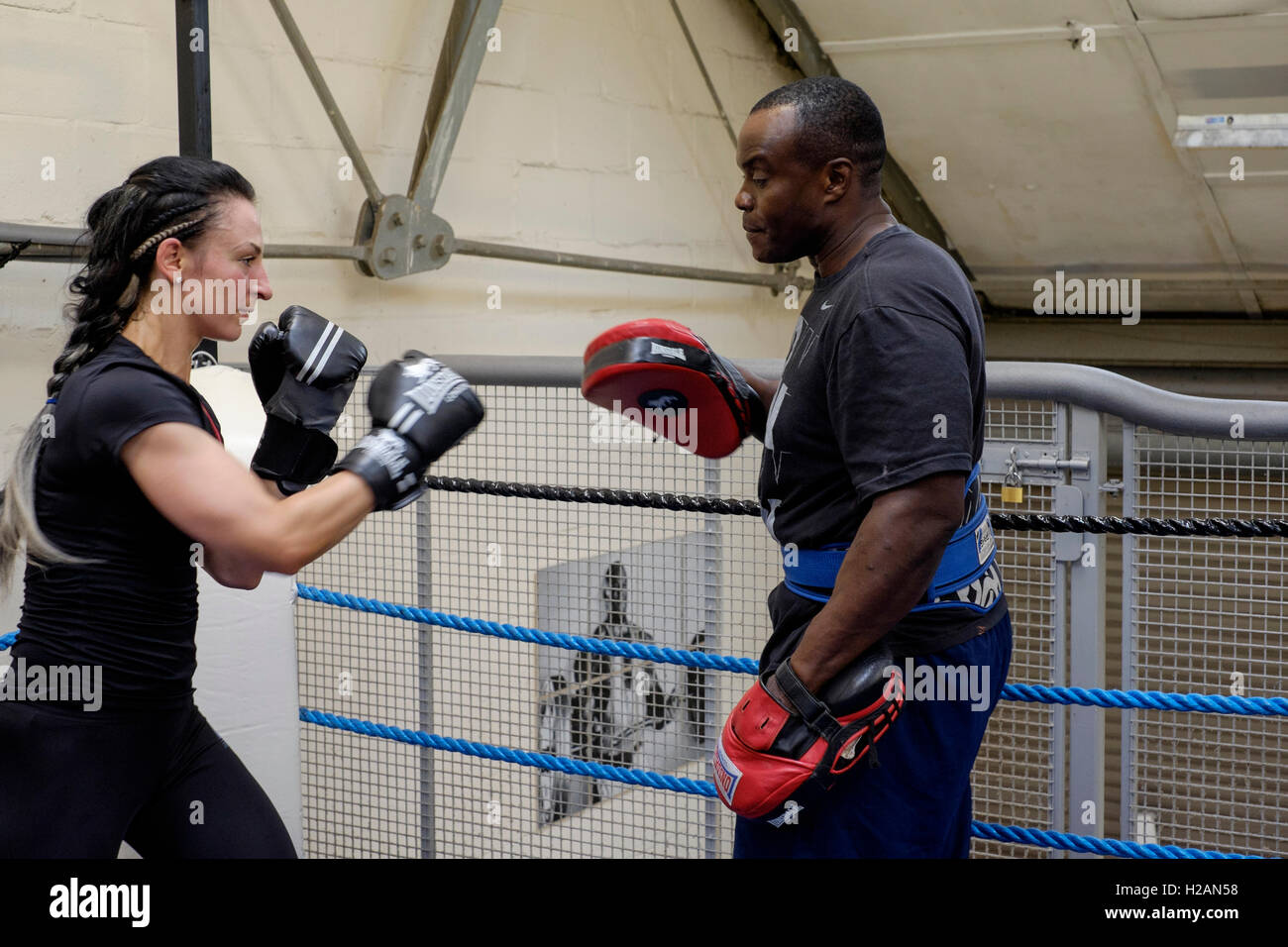young female working out sparring with male boxing trainer in a gym ...