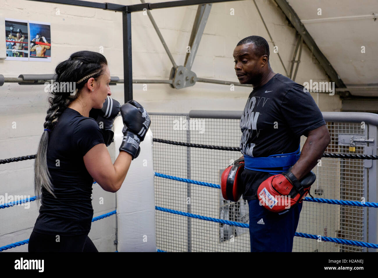 young female working out sparring with male boxing trainer in a gym ...