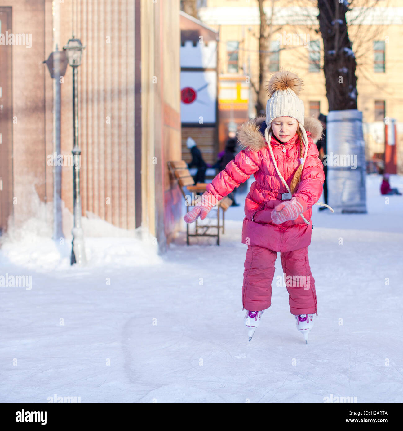 Adorable happy little girl enjoying skating at the icerink Stock Photo